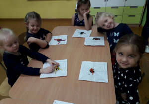 Dzieci przy stolikach lepią pająka z plasteliny.